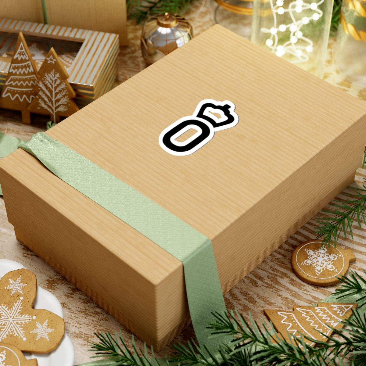 Wooden gift box with a green ribbon and a logo on a festive background with cookies and lights.