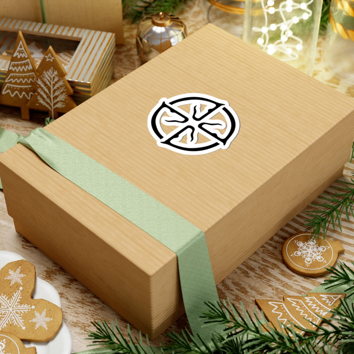 Wooden gift box with a green ribbon and decorative logo on a festive background with cookies and lights.