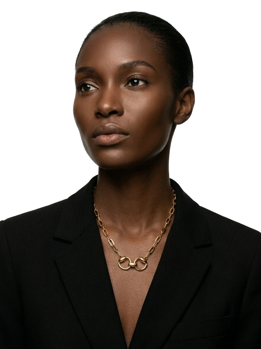 Woman wearing a black blazer and gold necklace against a white background