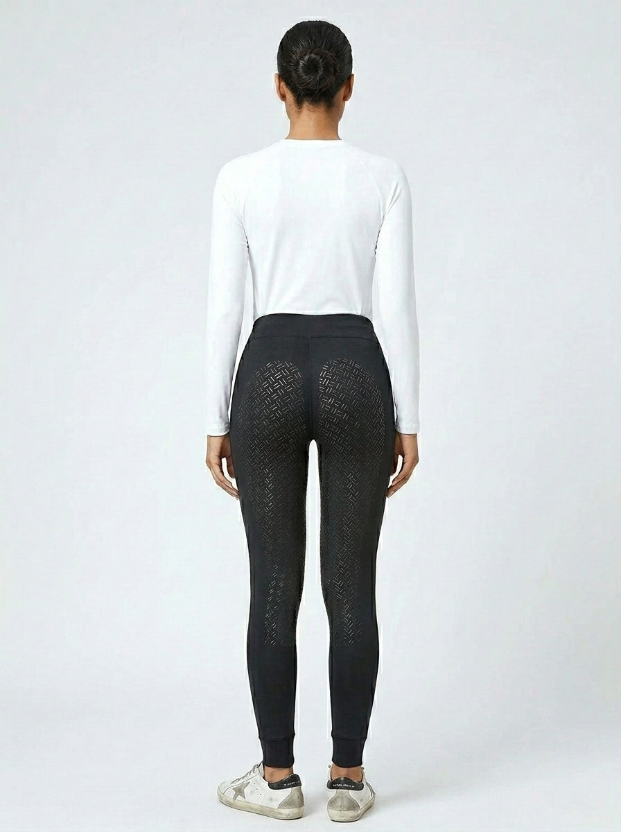 Women's black full-seat riding tights showing full-seat silicone grip panel from behind, white base layer and Golden Goose sneakers