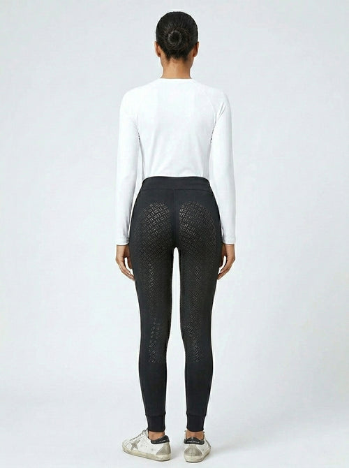 Women's black full-seat riding tights showing full-seat silicone grip panel from behind, white base layer and Golden Goose sneakers